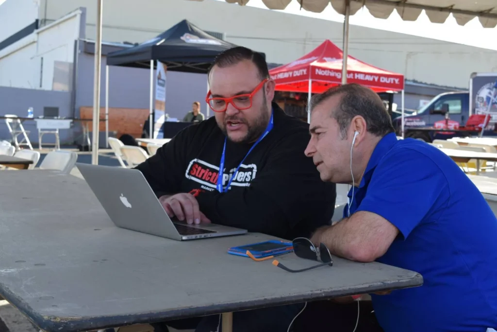 Two men sitting watching the computer.